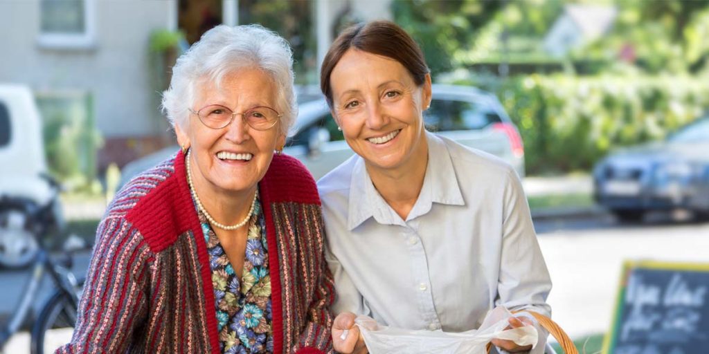 Une préposée souriante aidant une personne âgée à faire son épicerie